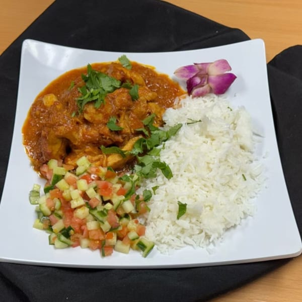 Taste of Curry's chicken curry with rice, a side salad, and an orchid garnish.