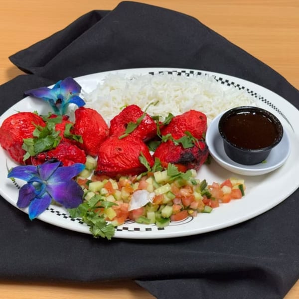 Taste of Curry's Chicken Tikka with rice, salsa, and sauce, garnished with orchids.